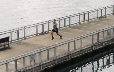 A man sprints down the middle of a jetty, his toes barely touching the dock.