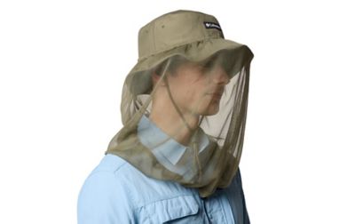 A man wears a brimmed hat with protective netting, dressed for outdoor conditions.