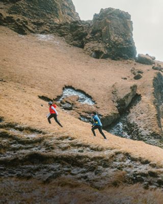 Two people hiking up a steep hillside. 