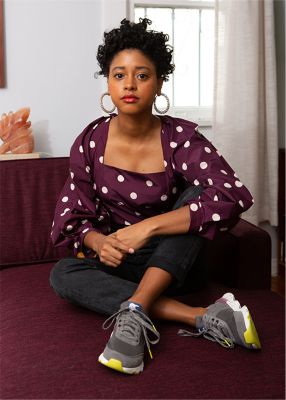 Candace Reels wearing Kinetic Lite Lace sneakers, sitting on a couch