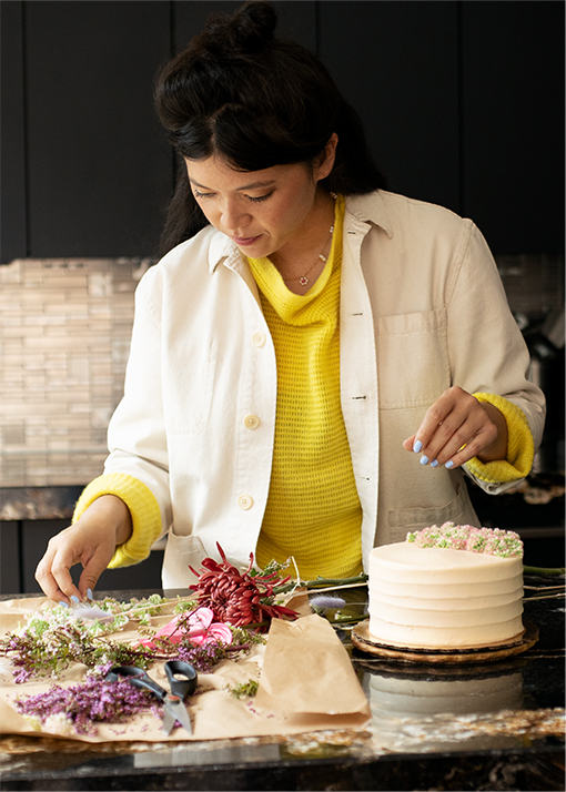 Natasha Pickowicz wearing decorating a cake in a kitchen