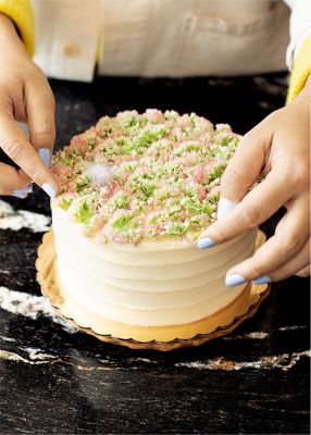 Natasha Pickowicz wearing decorating a cake in a kitchen
