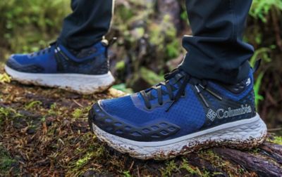 A pair of feet wearing muddy Columbia hiking shoes.