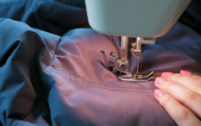 Jacket stitching being mended by a sewing machine.  