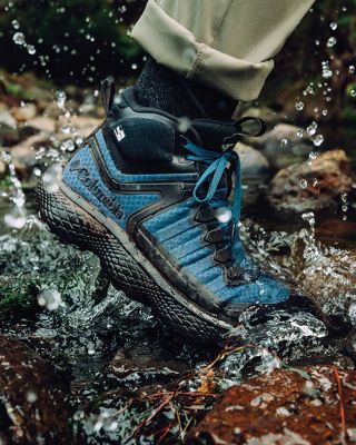 Close up of a waterproof hiking shoe splashing in a puddle.