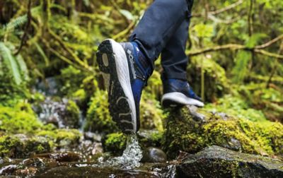 Gros plan d'une personne portant des chaussures Columbia Sportswear marchant dans un ruisseau.