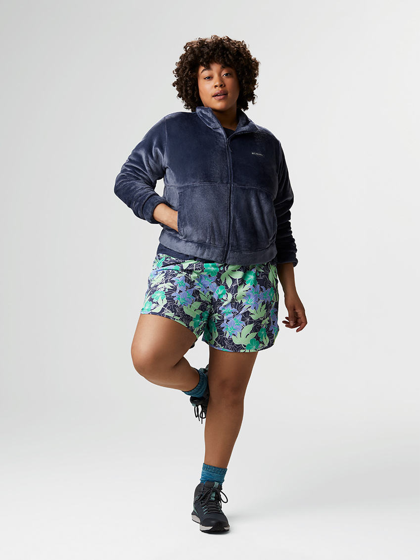 Woman in a fuzzy blue fleece jacket, blue floral-patterned shorts, blue socks, and hiking boots.