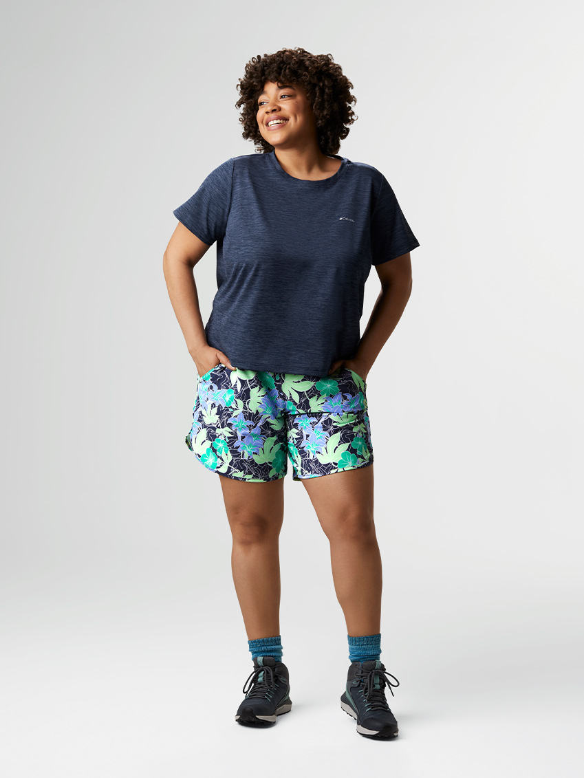 Woman in a navy t-shirt, blue floral-patterned shorts, blue socks, and hiking boots.