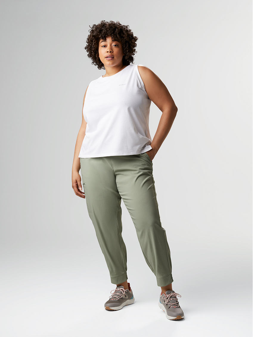 Woman in a white tank top and light beige jogger pants.