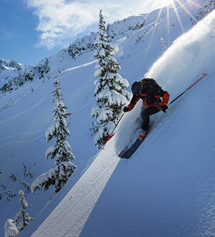 A skier going down a snowy mountainside. 