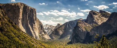 The expansive beauty of Yosemite National Park featuring the large rock formations towering above the forested valley below. 