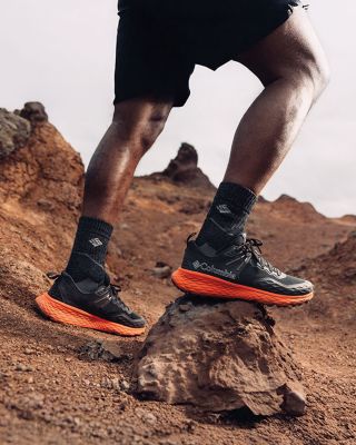A person trail running on dusty, rocky path
