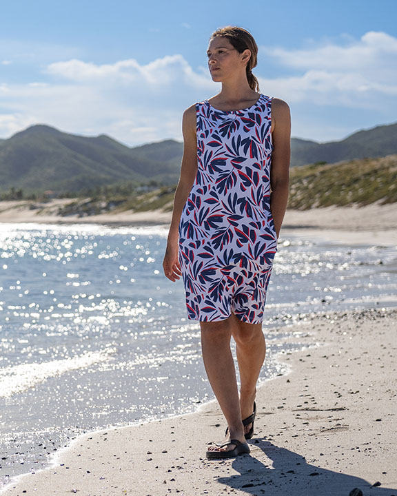 A woman walking on the beach in a colorful printed dress.