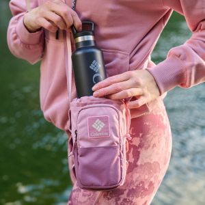Close-up shot of a woman placing a water bottle into a pink hip pack.
