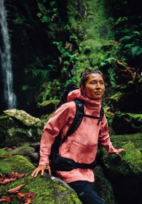 A hiker in a pink rain jacket exploring a forest with the text: Mother's Day Is May 11th