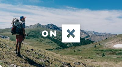 Hiker in a vast landscape with the onX maps logo.