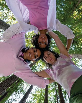 Friends circled up and smiling in a forest