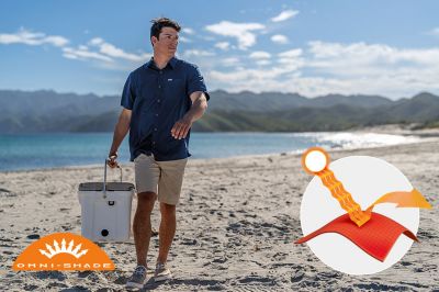 Model on a beach with a cooler. Omni-Shade logo is on the bottom left and a graphic showing how the sun's rays are blocked by fabric is on the bottom right.