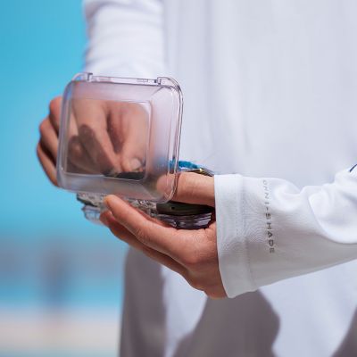 Close up of hands holding a tackle box with extended sleeves.