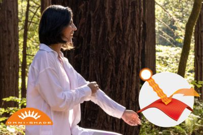 A woman on a hike wearing the Boundless Trek layer shirt. Omni-Shade logo is on the bottom left and a graphic showing how the sun's rays are blocked by fabric is on the bottom right.