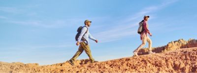 A couple hiking in the desert wearing sun blocking gear.