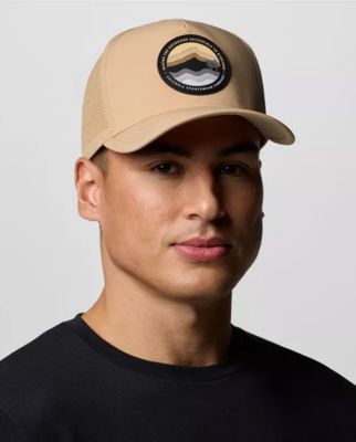 A tan baseball hat with a mountain logo on the front.