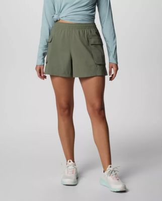 Waist-down image of a woman wearing green shorts and sneakers.