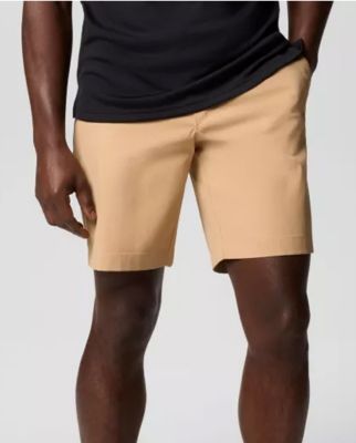 Waist-down image of a man wearing tan shorts and sneakers.