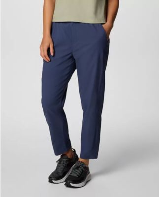 Waist-down image of a woman wearing navy pants and sneakers.