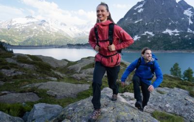 Two hikers happily walk up a rocky trail enroute to another summit. 
