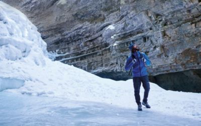 A man hikes through the snow as he gazes upwards at a peak he’d like to climb. 