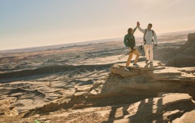 Two hikers celebrate the successful ascent of a high plateau with a high-five. 