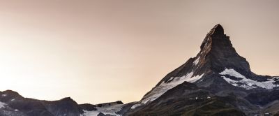 Dramatic photo of steep, pyramid-like peak with glacier field below. 