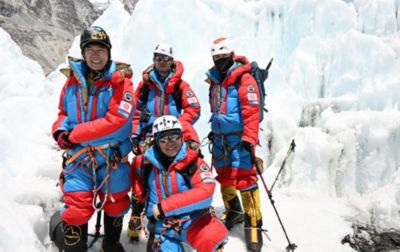 Four men, all wearing the Columbia Attack Suit, stand in front of a steep, massive glacier while training near Mt. Everest Base Camp. 