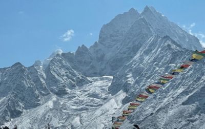 Prayer flags fly in the foreground, with the majestic peak looming in the distance. 