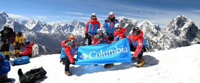 Six mountain climbers, all wearing Columbia Sportswear's apparel, raise a Columbia banner on the summit of Mt. Lobuche while training for Mt. Everest. 