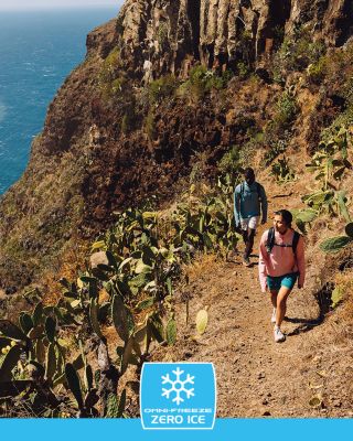 Friends hiking along a sunny coastline in cooling hiking gear.