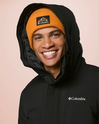 A man smiling wearing a green jacket and beanie.