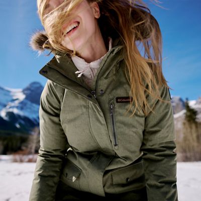 A woman bundled up in Columbia snow gear throwing a snowball.