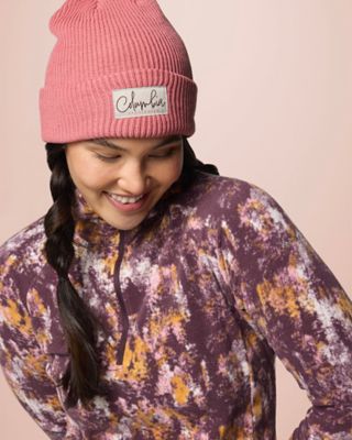 A woman smiling in a beanie and cozy fleece jacket.