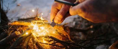 A person sparks kindling using flint and steel.