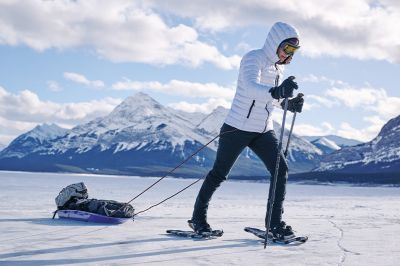 A person snowshoeing with a snow-capped mountain range in the background.