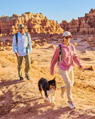 Friends hiking along a sunny coastline in cooling hiking gear.