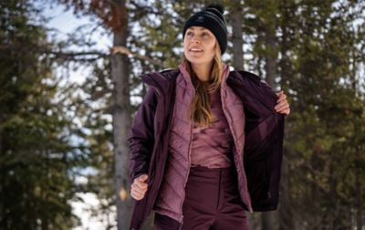 A woman wearing a Columbia 3-in-1 Interchange parka demonstrates how the quilted lining can be worn separately from the waterproof shell.