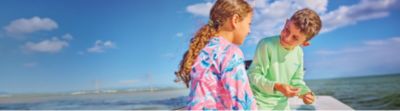 Two kids on a boat getting ready to fish.