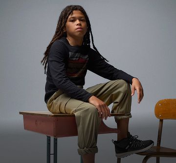 A boy sitting on a school desk.