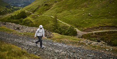 A person wearing an OutDry Extreme Eco jacket walking up a stony path.