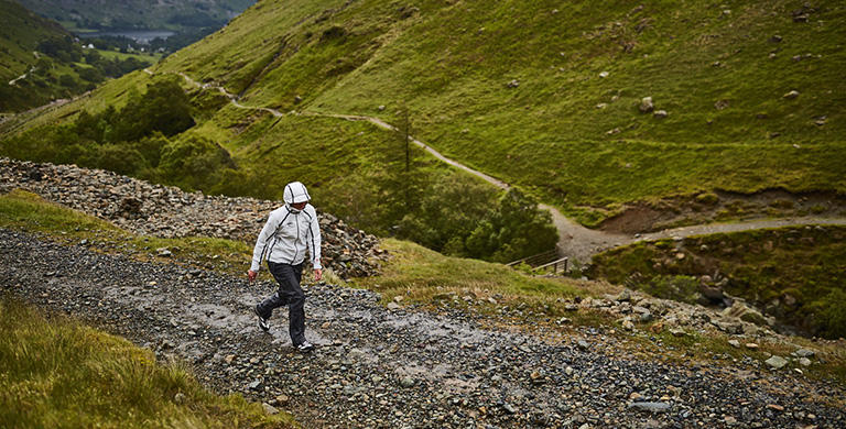 A person wearing an OutDry Extreme Eco jacket walking up a stony path.