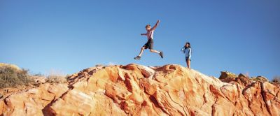 Two kids running along a rocky ridge.
