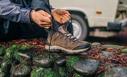 A man lacing up a hiking shoe with TechLite cushioning.